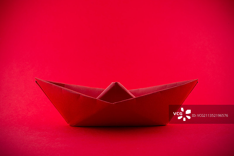 红色背景下的纸船特写图片素材