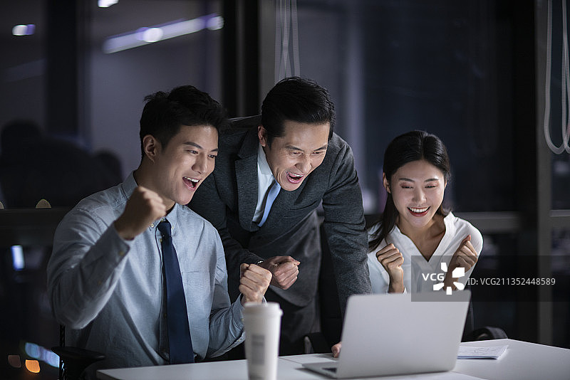 晚上加班的商务人士一起挥臂庆祝图片素材