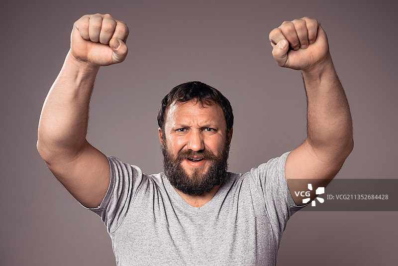 在灰色背景下展示肌肉的微笑年轻男子肖像图片素材