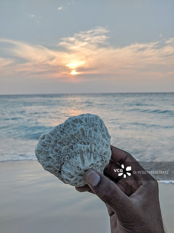 裁剪过的手在日落时于印度安达曼和尼科巴群岛的南安达曼海滩拿着冰块图片素材