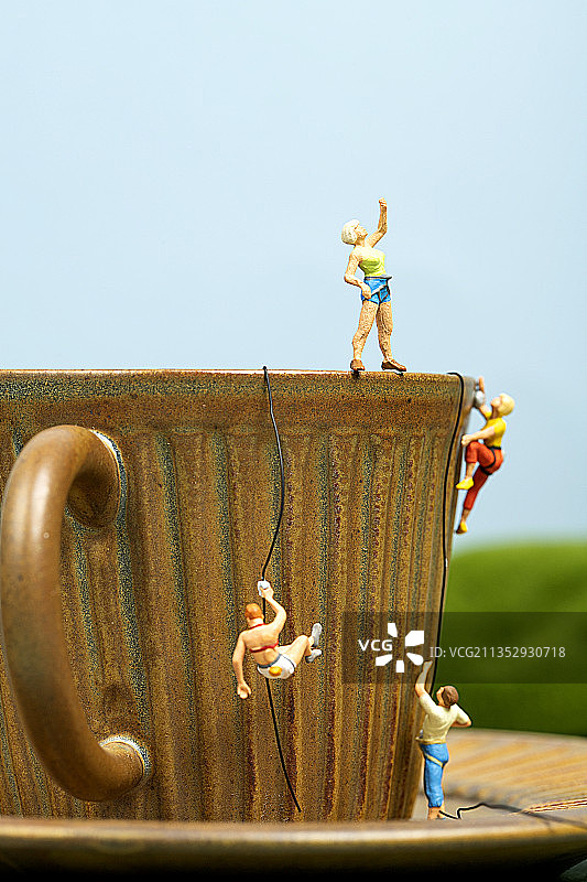 咖啡杯上攀岩的微缩小人景观图片素材