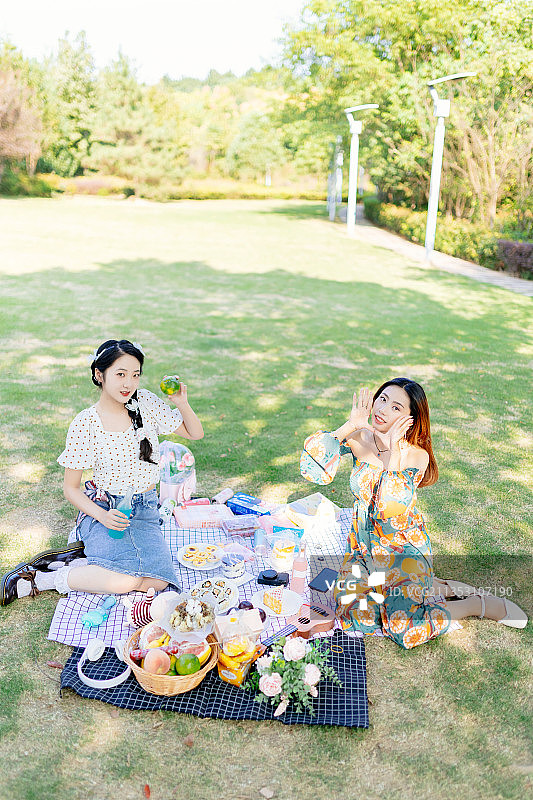 两个亚洲青年美女闺蜜在户外野餐垫上野餐图片素材