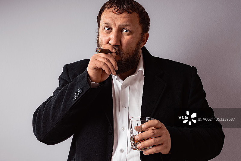站在灰色背景前抽雪茄的男人肖像图片素材