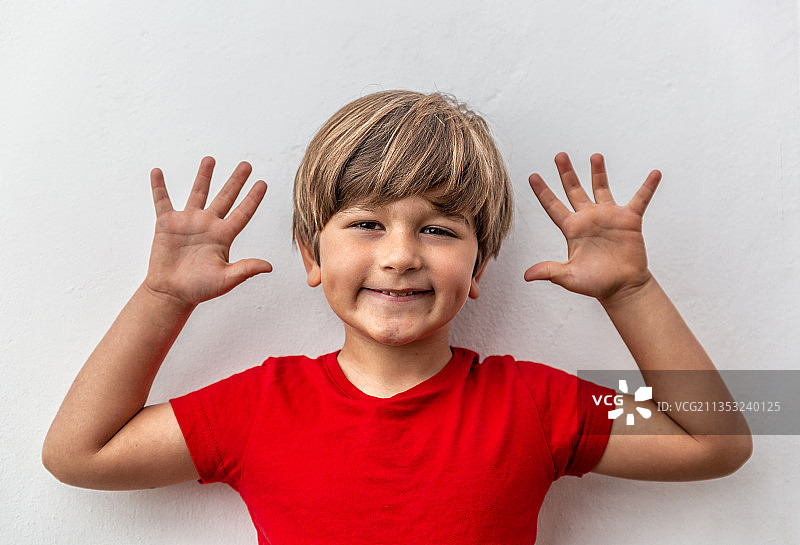 白色背景下做手势的微笑男孩图片素材