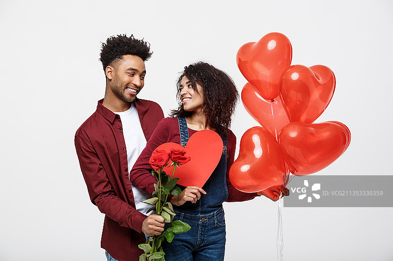 情侣手拿红色心形氦气球，站在白色背景前图片素材