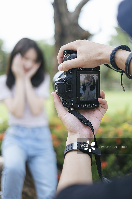 模特女孩在ixora bush拍照时的过肩照。图片素材