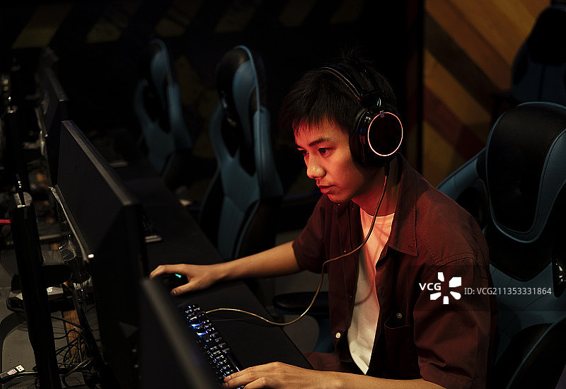 泰国职业玩家在红色霓虹灯下玩电脑游戏。愤怒的狂热玩家。图片素材
