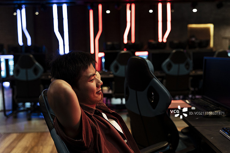 赢得最后一场比赛后，快乐的亚洲玩家在游戏椅上放松。图片素材