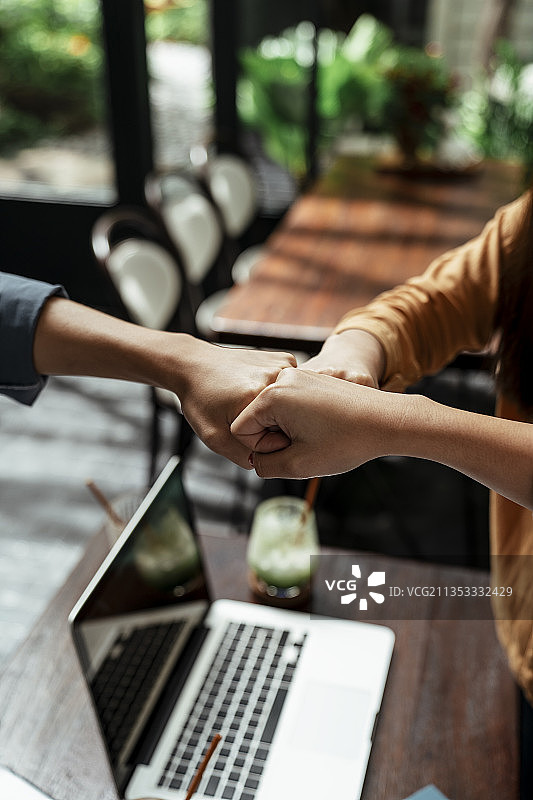 三个商人用三个手碰拳。团队合作的概念。图片素材