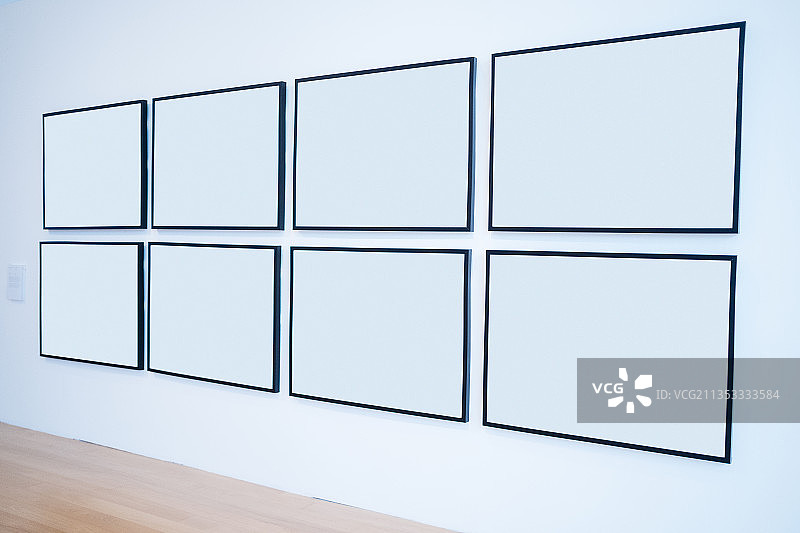 墙上挂着八个空白的白色相框。艺术画廊。图片素材