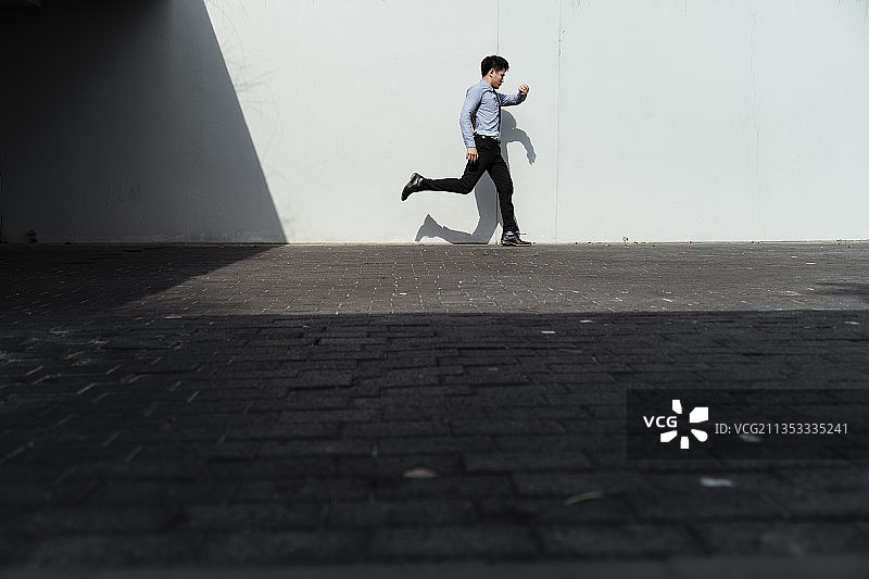 跑步的生意人看了看表，跑到办公室锻炼。图片素材