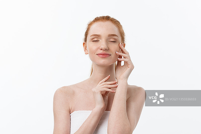 女人在白色背景下往脸上涂抹面霜图片素材