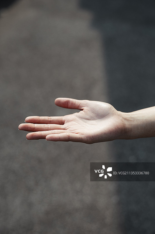 女人的手在阳光下与阴影在鹅卵石地板上。图片素材