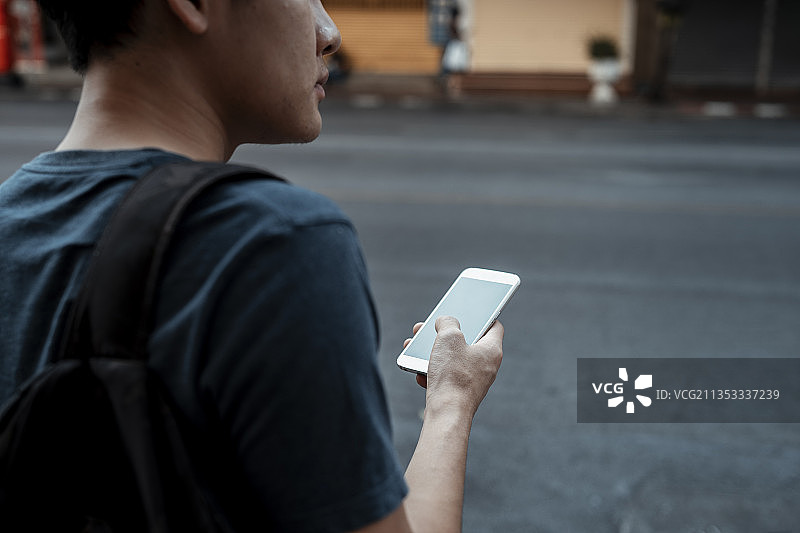 一名亚洲游客用智能手机叫出租车在街上接他。图片素材