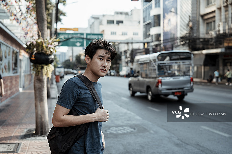 亚洲背包客游客在曼谷的人行道上等待出租车。图片素材