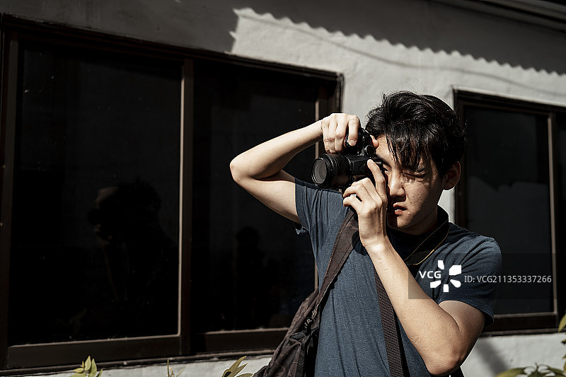年轻英俊的亚洲摄影师男子拍照与相机-复制空间。图片素材
