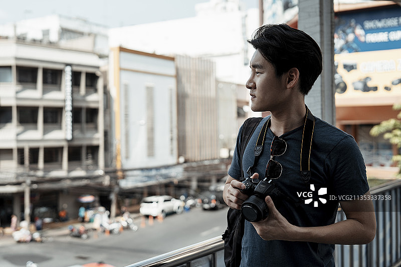 复制空间-年轻英俊的亚洲摄影师男子步行在曼谷城市。图片素材