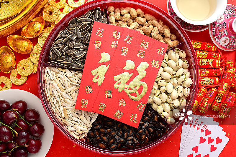 红色喜庆背景上的零食、水果、元宝、功夫茶、鞭炮——春节新年图片素材