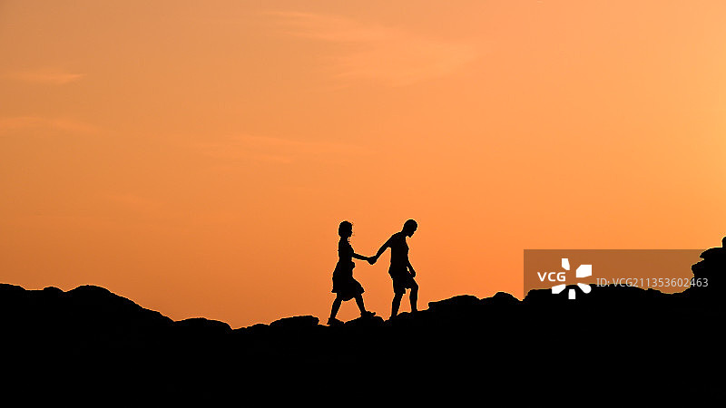 情侣在日出时分携手走在山顶图片素材