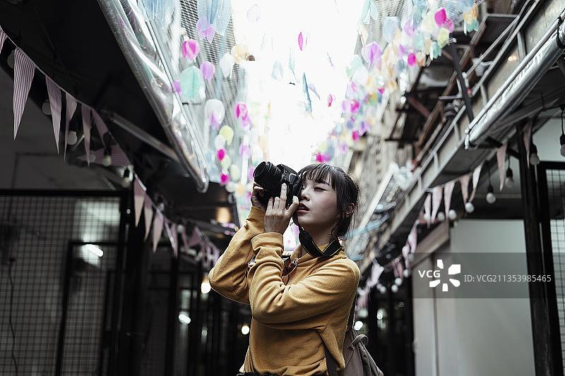 美丽可爱的卡哇伊漂亮的亚洲女性摄影师在节日活动中用相机拍照。图片素材