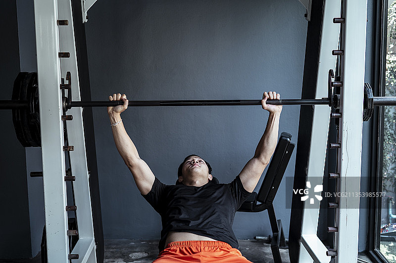 亚洲运动员泰国运动员在健身房杠铃卧推站锻炼。图片素材