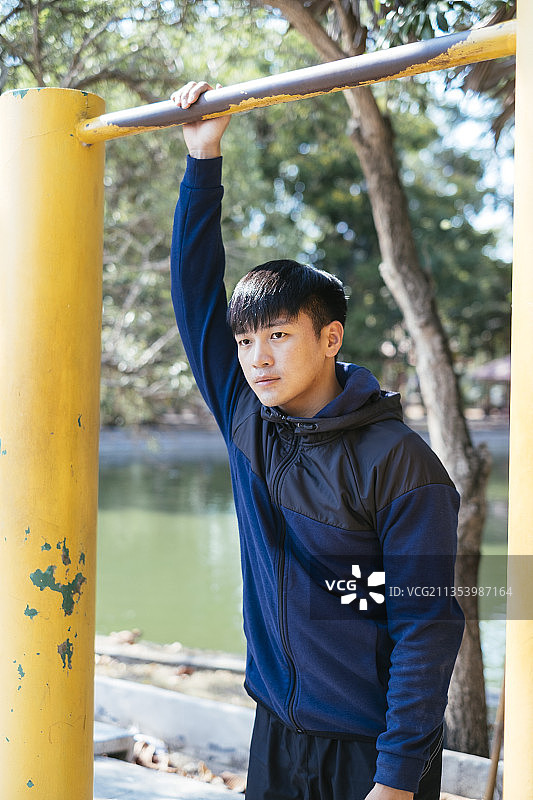 运动亚洲泰国人在黑色运动服做拉在公园的黄条。河的背景。图片素材