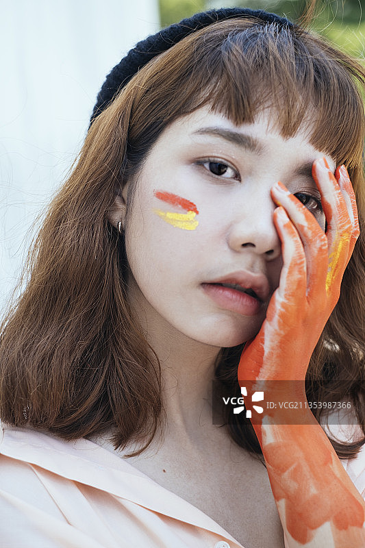 漂亮的潮人亚洲泰国艺术家在长衬衫。橙色液体的脏手。肮脏的艺术家。橙色的手。图片素材