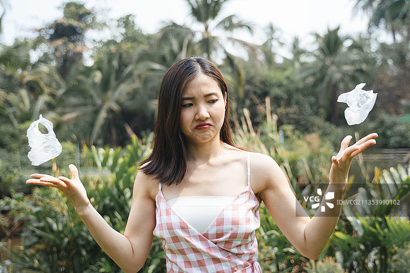 愤怒愤怒的亚洲女孩讨厌粉红色的衣服塑料袋。拯救世界。全球变暖。从塑料垃圾中拯救地球。用双手捧着皱巴巴的塑料袋。投掷聚合物塑料袋。图片素材