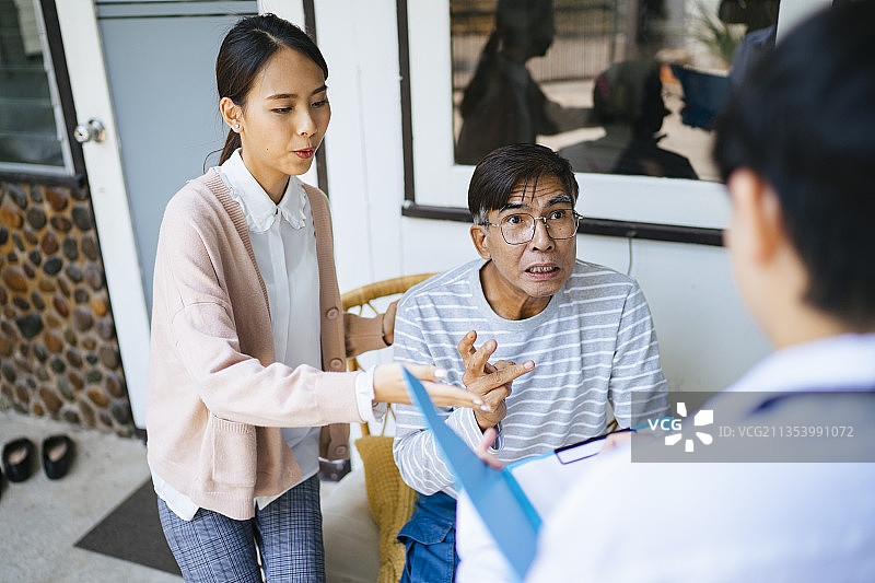 一位白发老人和他的女儿在家访期间向医生讲述了他的病情。图片素材
