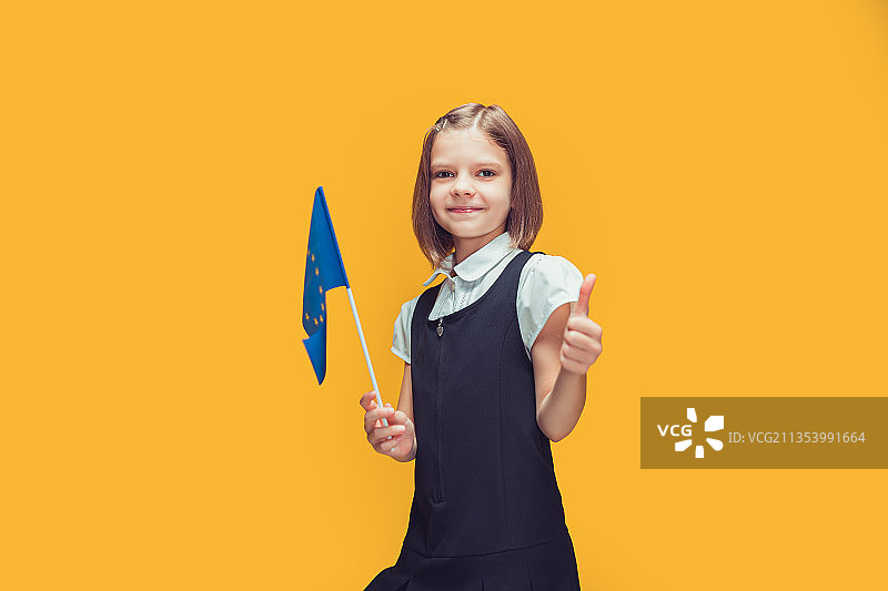 女孩站在黄色背景前，拿着道具的肖像图片素材