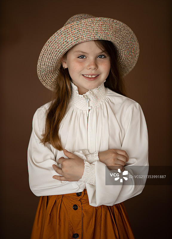 戴帽子站在棕色背景前的女孩，德国图片素材