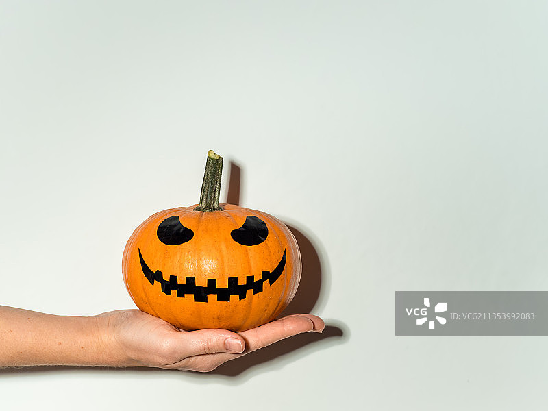 裁剪过的手拿着万圣节南瓜灯，白色背景图片素材