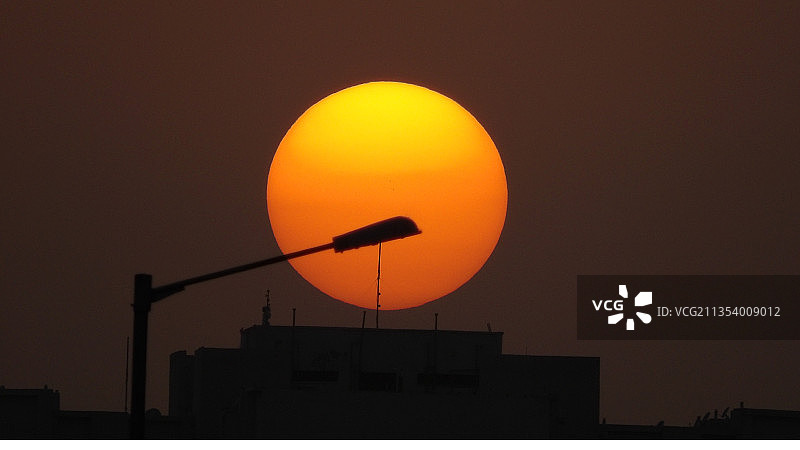 印度哈里亚纳邦法里达巴德，橙色天空下的路灯轮廓图片素材