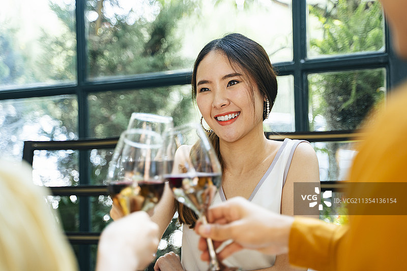 美丽的亚洲女人与朋友在餐厅聚会。向酒杯敬酒。欢呼。朋友们用香槟庆祝。图片素材