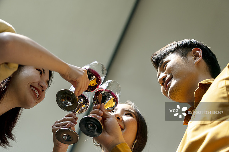 底部视图-三个亚洲人在敬酒。图片素材