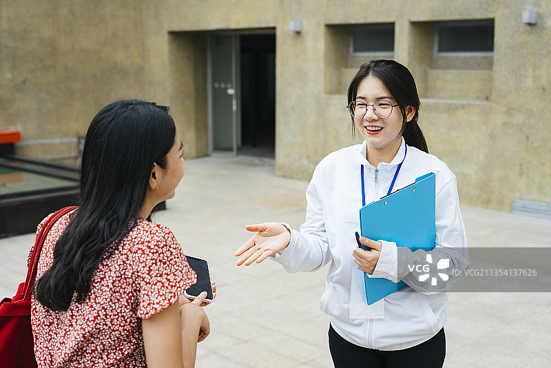 开朗的亚洲女导游正在跟游客讲解这个地方的细节。图片素材