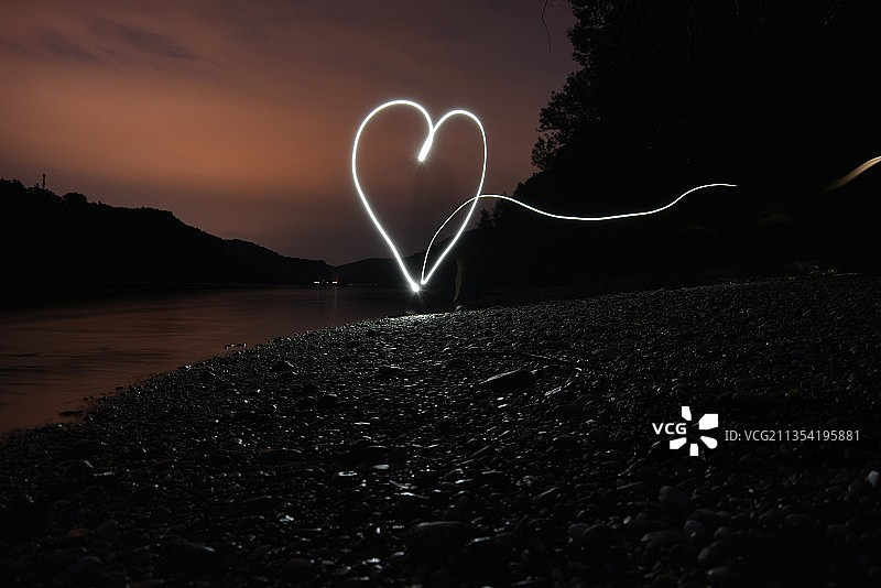 夜晚，湖边岩石上的心形剪影图片素材