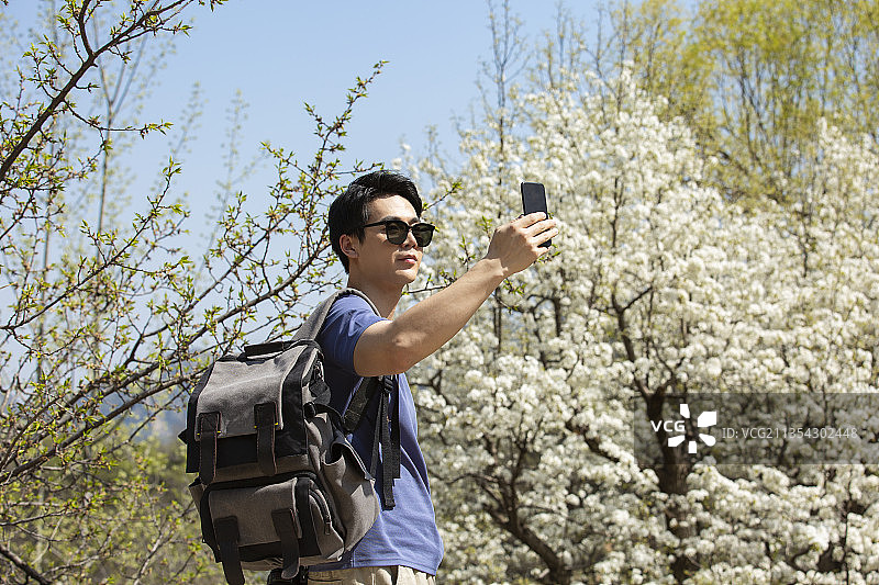 青年男子在户外旅行用手机拍照图片素材