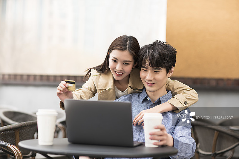年轻情侣在咖啡厅网上购物图片素材
