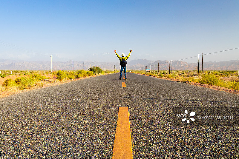 一位背包的男性中国人独自走在中国新疆戈壁公路上图片素材