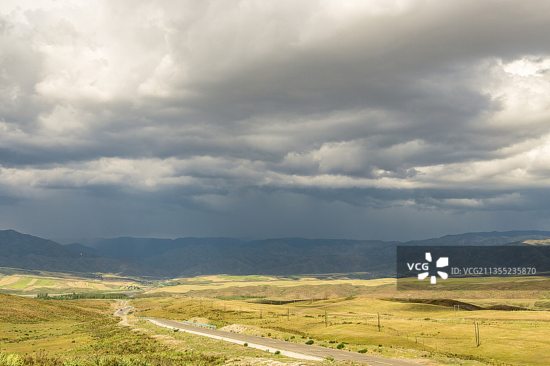 阴天积雨云下中国新疆的山坡草原村庄图片素材