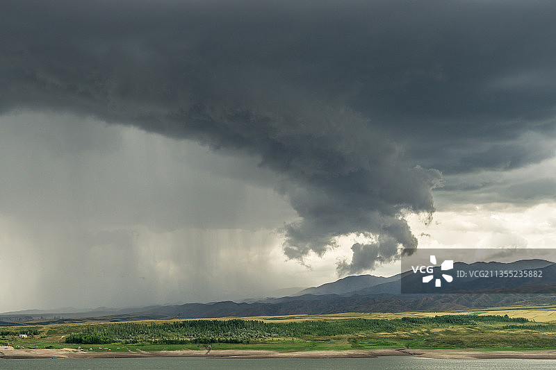 阴天积雨云下中国新疆的山坡草原村庄图片素材