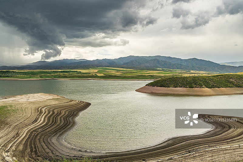 阴天积雨云下中国新疆的山坡草原村庄图片素材