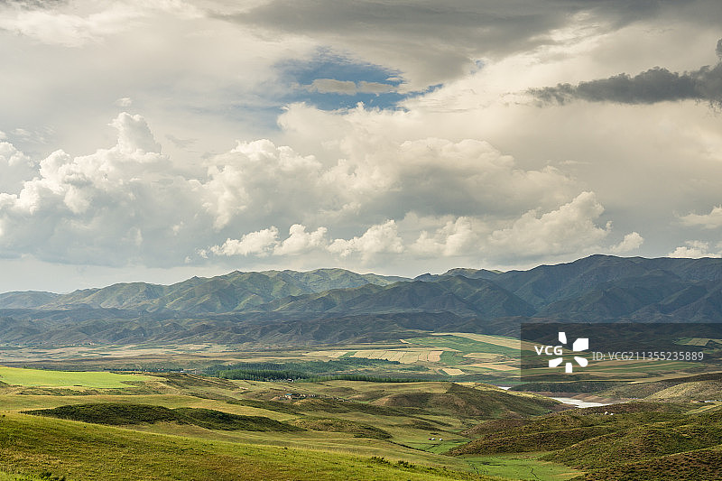 阴天积雨云下中国新疆的山坡草原村庄图片素材