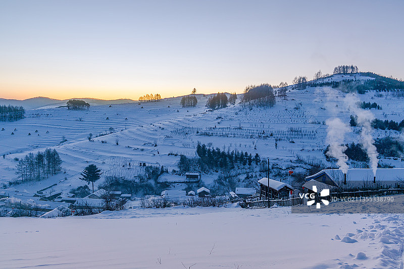 日出下的中国吉林延边大兴安岭的雪地树林和村庄图片素材