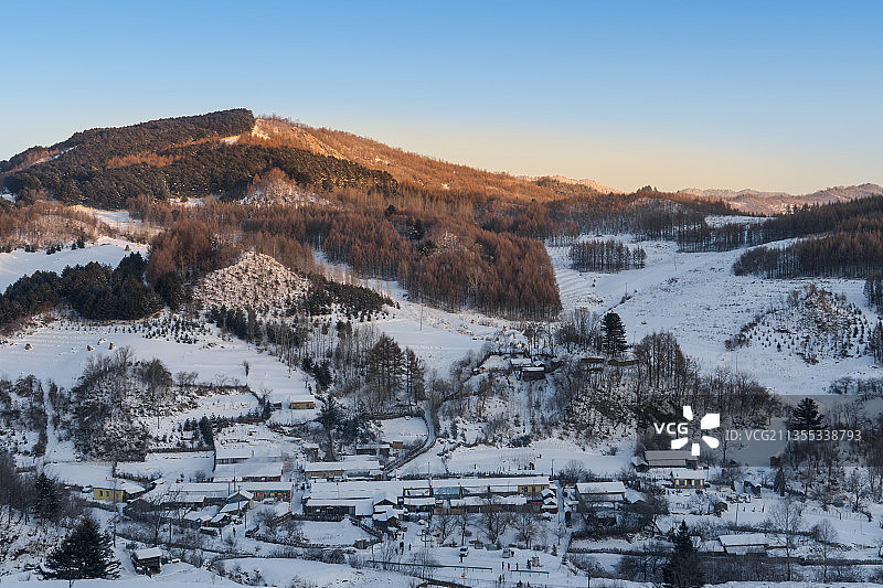 日出下的中国吉林延边大兴安岭的雪地树林和村庄图片素材