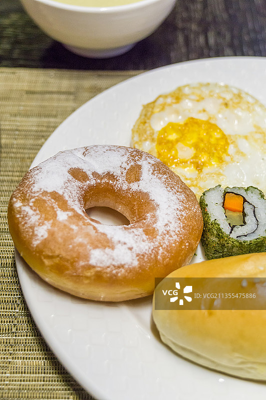 一盘有煎蛋面包甜甜圈玉米的自助早餐图片素材