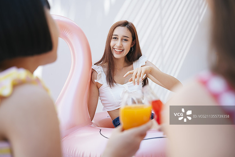 性感的女人在夏天的派对上和朋友出去玩。喝果汁，与人敬酒。夏季派对在长周末假期。图片素材