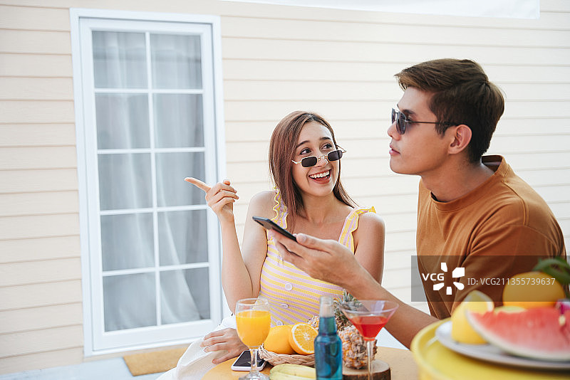 一对快乐的情侣在夏日的热带酒吧度假，享受美好时光。图片素材