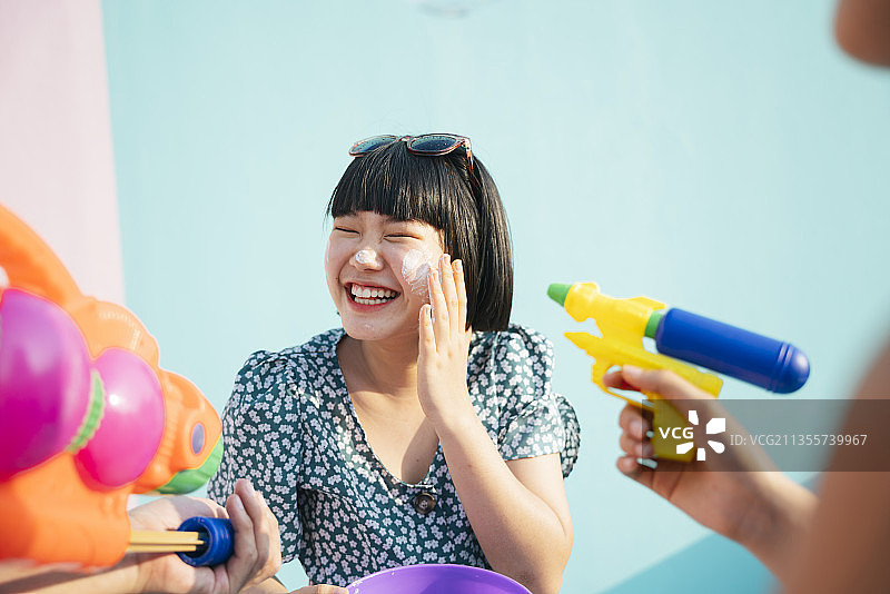 波波发型可爱美丽的女子在泼水节与人们嬉戏。曼谷的泼水节。孤立在蓝色背景上。图片素材